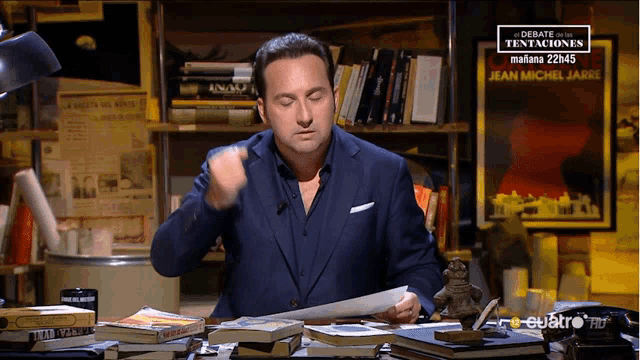 a man sitting at a desk with books and a sign that says debate tentaciones on it