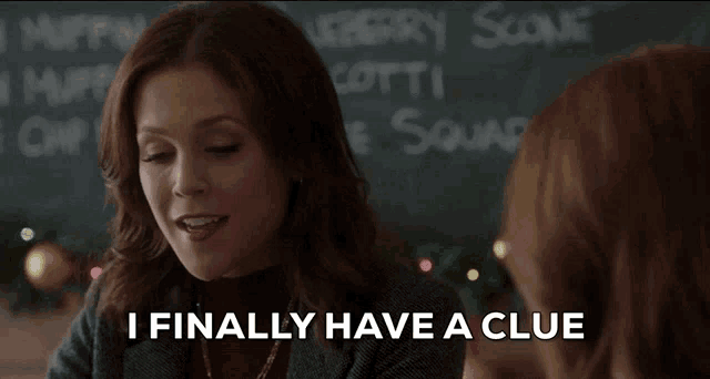a woman says " i finally have a clue " in front of a blackboard