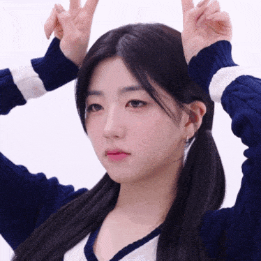 a girl in a blue and white sweater makes a peace sign with her hands