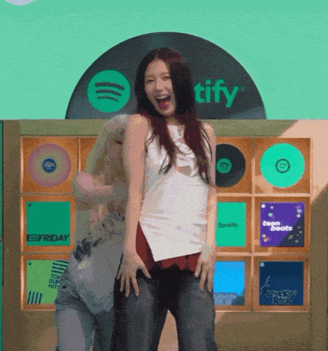two women dancing in front of a spotify sign