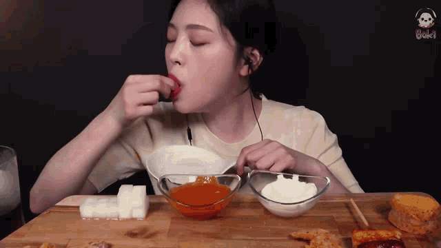a woman is sitting at a table with a bowl of sauce in front of her .