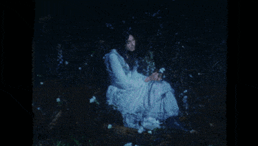 a person in a white dress is laying in the grass with flowers