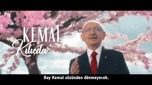 a man in a suit and tie stands in front of a cherry blossom tree with kemal kilicdar written on it