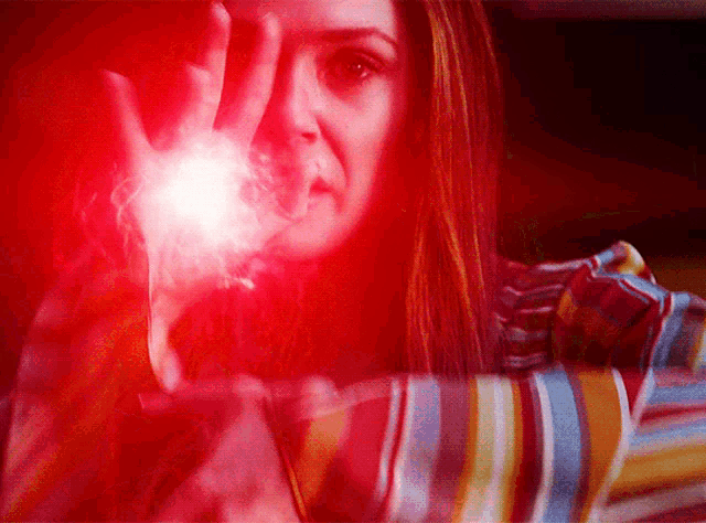 a woman with red hair is holding a red light in her hand .
