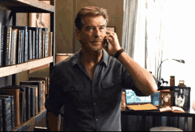 a man is talking on a cell phone in front of a bookshelf with a book titled " a brief history " on it
