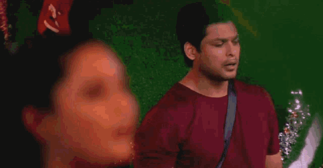 a woman with a ponytail is smiling in front of a man in a red shirt