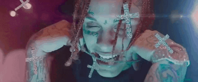 a close up of a person with dreadlocks and a cross on their face and arms .