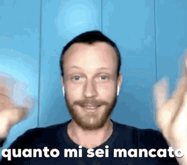 a man with a beard is wearing ear buds and has the words quanto mi sei mancato above him .