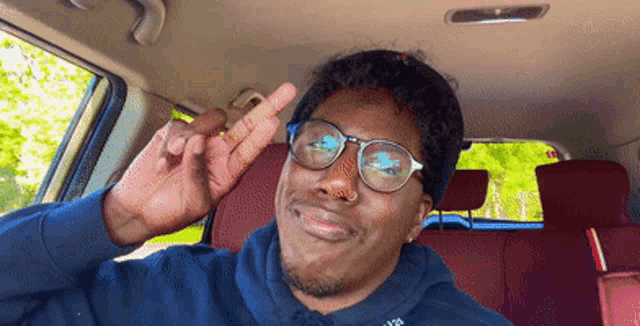 a man wearing glasses is giving the middle finger in a car