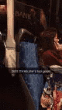 a woman is sitting on a bus looking at her phone .