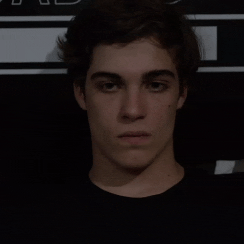 a young man in a black shirt is standing in front of a black and white wall