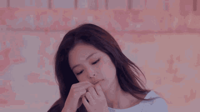 a woman covering her mouth with her hand and looking at the camera