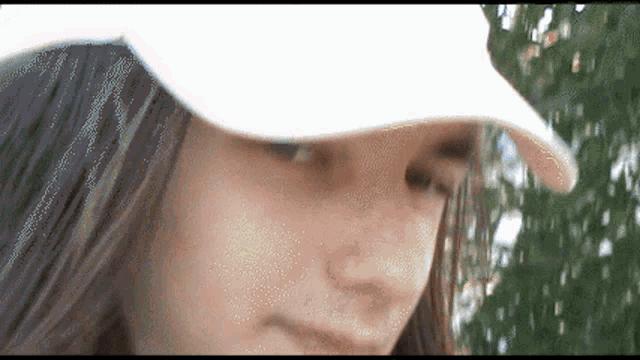 a woman wearing a white hat looks down at something