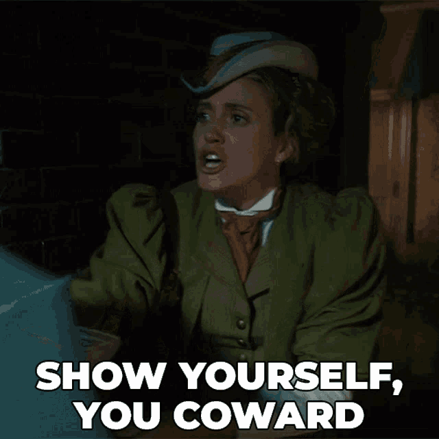 a woman in a green coat and hat says " show yourself you coward "