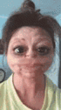 a woman in a yellow shirt is making a funny face with her eyes closed .