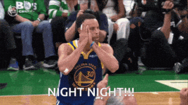 a basketball player from the golden state warriors is sitting on the court with his hands on his head .