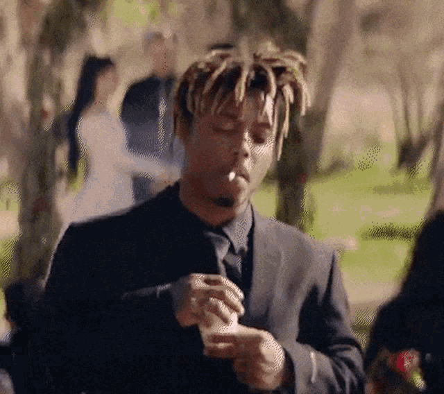 a man in a suit is smoking a cigarette and holding a cup .