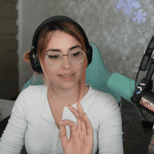 a woman wearing glasses and headphones is giving the ok sign