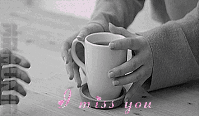 a black and white photo of a person holding a cup with the words i miss you