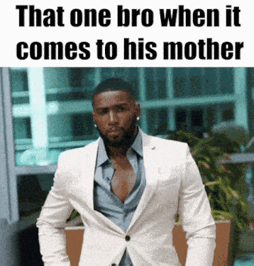 a man in a white suit is standing in front of a sign that says " that one bro when it comes to his mother "