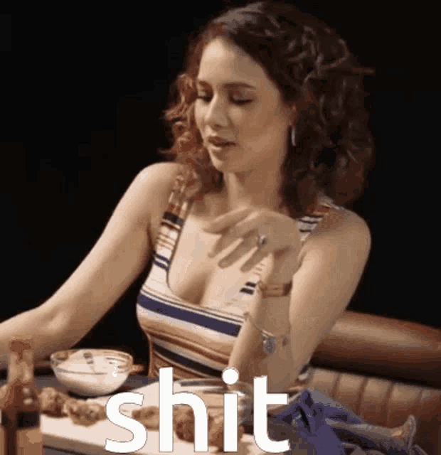 a woman sitting at a table with the word shit written in white