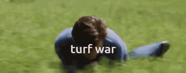 a man is laying on the grass with the words `` turf war '' written on the bottom .