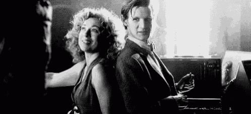 a black and white photo of a man and a woman sitting next to each other .