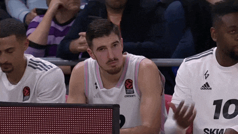 a basketball player with the number 10 on his shirt sits in the stands