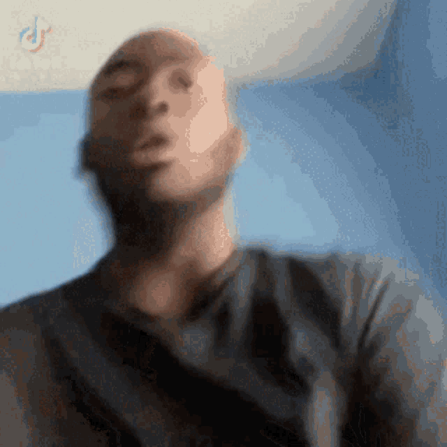 a bald man with a beard is making a funny face while wearing a grey shirt .