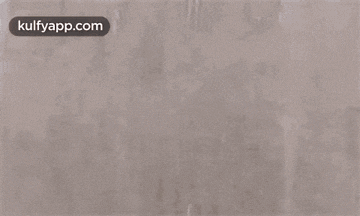 a man with red paint on his face is reaching for something on a wall .