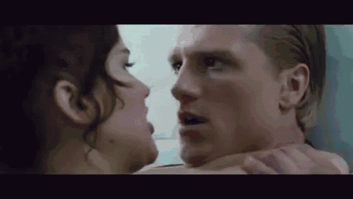a man and a woman are kissing in a bathroom and the woman is holding the man 's neck .