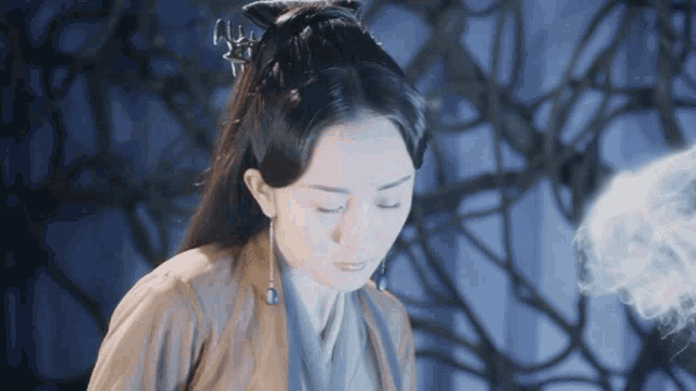 a woman with her eyes closed is standing in front of a tree