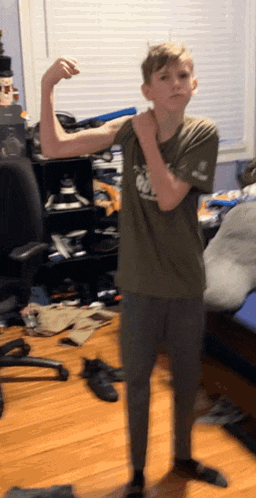 a young boy in a green shirt flexes his muscles