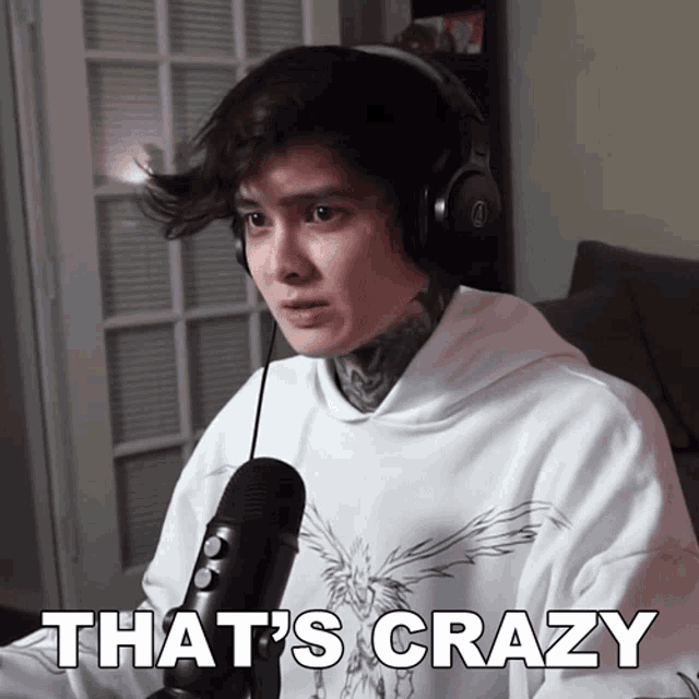 a man wearing headphones says that 's crazy while sitting in front of a microphone