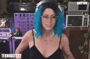 a woman with blue hair and glasses stands in front of a microphone and a sign that says teknokat222