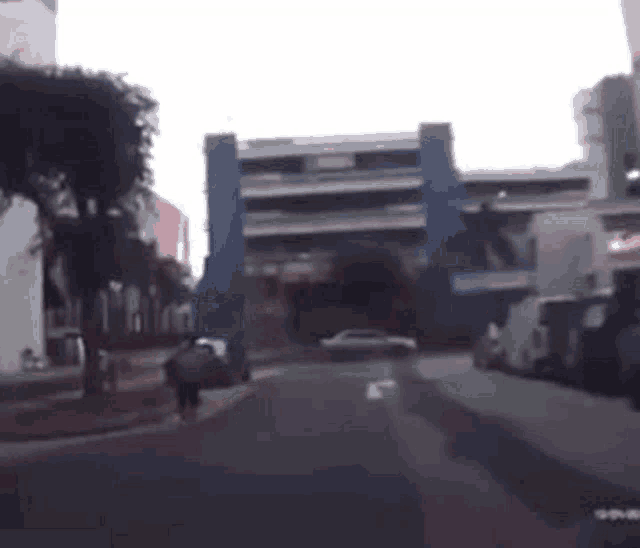a car is driving down a street in front of a building with a blue building in the background .