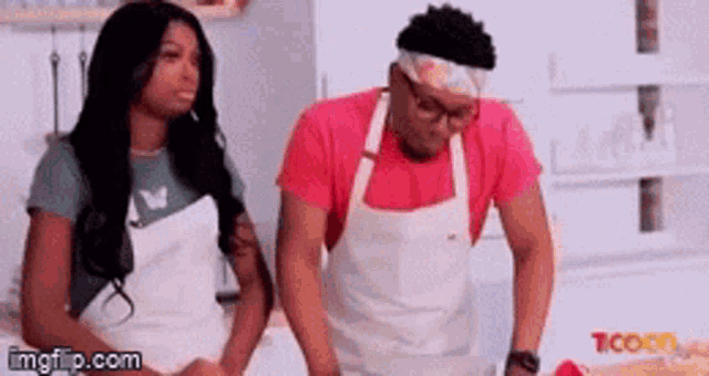 a man and a woman in aprons are standing next to each other in a kitchen