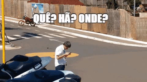 a man is looking at his phone in front of a sign that says ' que ha onde '