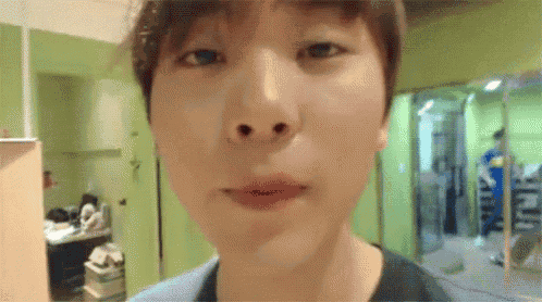 a close up of a young man 's face with a green wall in the background .