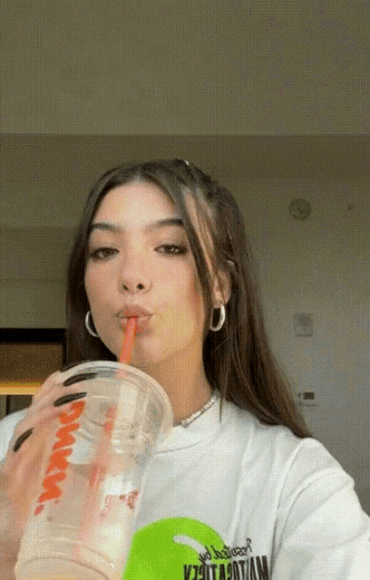 a woman drinking from a cup that says dunkin ' donuts