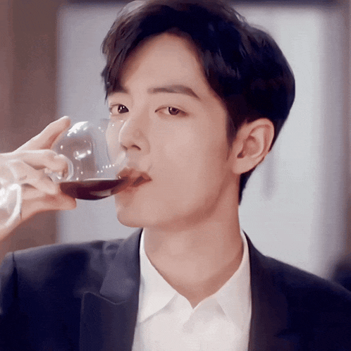 a man in a suit drinks from a glass