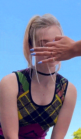 a woman with blue nails and a choker covering her eyes with her hands