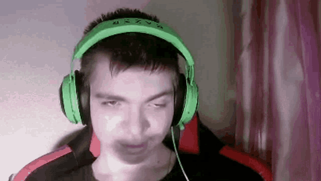 a man wearing green headphones is making a face .