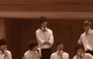 a group of young men in white shirts and bow ties are sitting in a room .