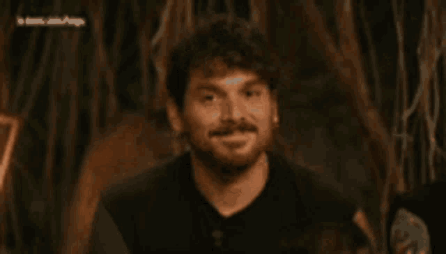 a man with a beard is making a funny face with his eyes closed in a dark room .