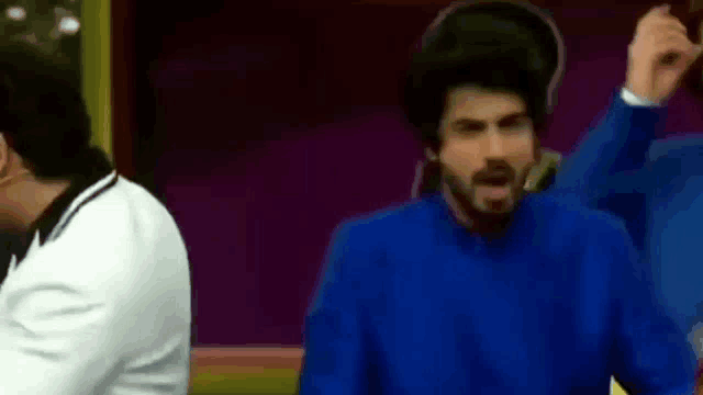 a man in a blue sweater is standing next to another man in a white suit .