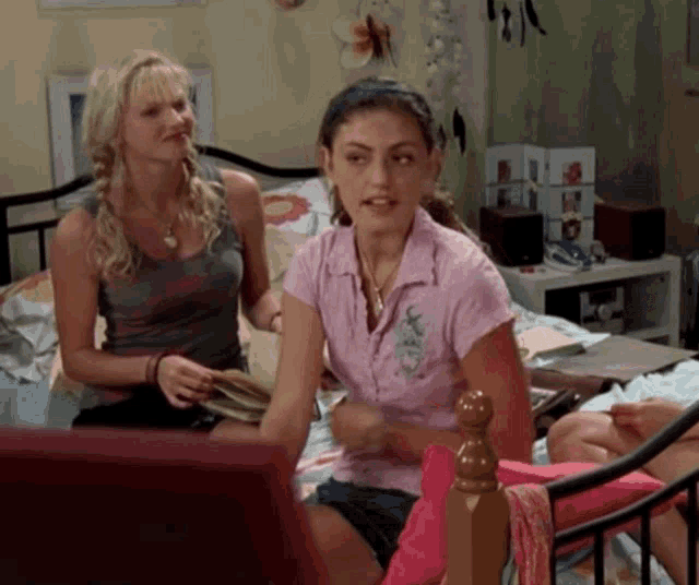 a woman in a pink shirt is sitting on a bed