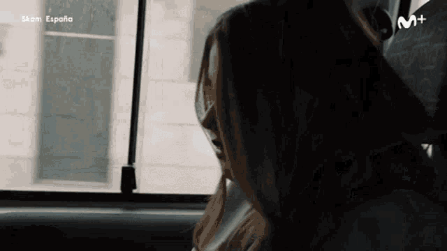 a woman is sitting in the back seat of a car looking out of the window .