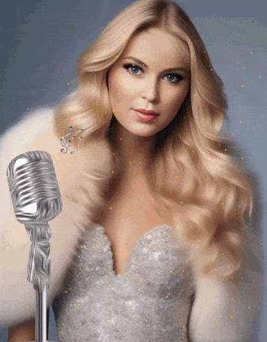 a woman in a silver dress is holding a microphone