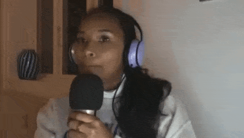 a woman wearing headphones is holding a microphone and talking into it .